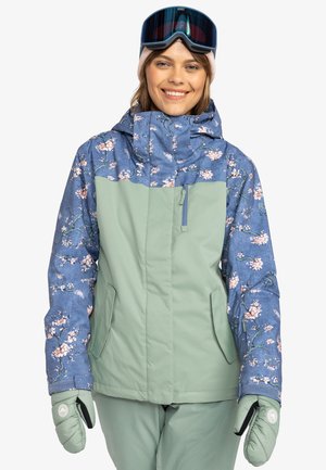 Damen Snowboardjacke mit einem oberen Teil in blauer Blumenmusterung und einem unteren Teil in einheitlichem Hellgrün. Sie besitzt eine Kapuze und Fronttaschen.