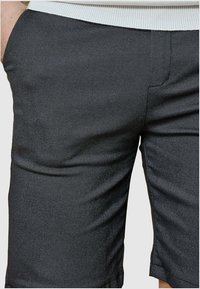 Shorts grises ajustés en tissu texturé, avec des poches latérales et une coupe légèrement fuselée. Taille élastique pour plus de confort.