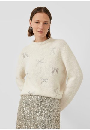 Witte gebreide trui met een gestructureerd afwerking en zilveren strikpatronen, gecombineerd met een gouden rok met pailletten. Ronde halslijn en een relaxte pasvorm.