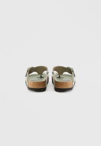 Πράσινες σάντες με φινίρισμα από φελλό, πίσω όψη. Ρυθμιζόμενη λουρί με μεταλλική αγκράφα, υφή βάσης, ανοιχτές πλευρές και στρογγυλή μορφή.