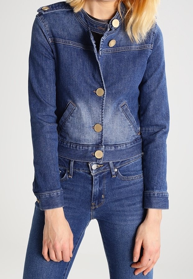 Tummansininen farkkutakki, jossa on hieman vaaleampi gradientti. Varustettu kultaisilla nappeilla, kahdella sivutaskulla ja lyhyemmällä leikkauksella.