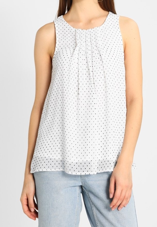 Mouwloos wit topje met zwarte stippen, met een geplooide halslijn en een losse pasvorm, gemaakt van een lichte stof.