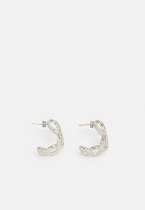 Boucles d'oreilles en argent avec un design torsadé et ondulé. Fabriquées en métal brillant, avec un fermoir pour un port sécurisé. Texture lisse, taille moyenne.