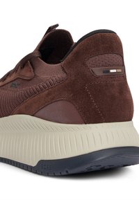 Sneaker en suède marron avec un upper en tricot texturé, une semelle intermédiaire beige rembourrée et une semelle en caoutchouc ; présente des accents de couleur subtils au niveau du talon.