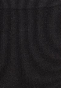 Κοντινή λήψη μαύρου ριμπ ύφασματος που δείχνει κάθετες υφασμάτινες γραμμές και λεπτομέρειες πλεκτού σχεδίου.