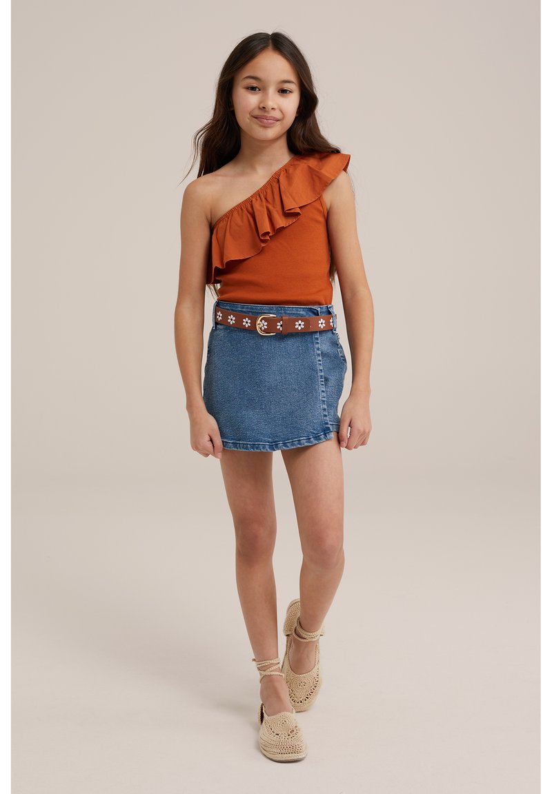 Top arancione a spalla unica con dettagli a volant, abbinato a una mini gonna di jeans blu, accentuato da una cintura floreale marrone e scarpe intrecciate beige.