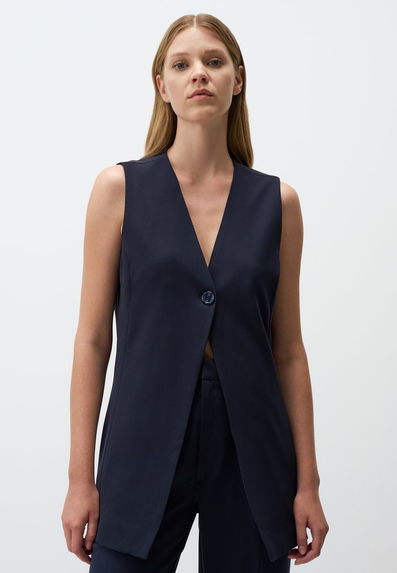 Gilet senza maniche blu navy con scollatura a V profonda, chiusura con un unico bottone, forma sagomata e tessuto liscio. Design semplice e moderno.