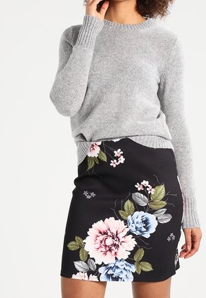 Grå strikket sweater med ribbede manchetter, parret med en sort blyantskirt med blomsterprint, der har store pink og blå blomster samt grønne blade.
