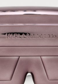 Fioletowe twarde etui z błyszcząca powierzchnią. Zawiera wytłoczony logo "KARL LAGERFELD" oraz kanciastą konstrukcję, która podkreśla nowoczesny i elegancki wygląd.