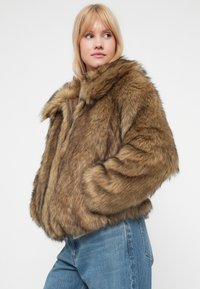 Giacca in pelliccia sintetica, marrone con striature più chiare, caratterizzata da un ampio colletto, chiusura con zip e silhouette boxy. Tessuto morbido, vestibilità oversize.