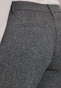 Grau gestreifter Stoff mit strukturiertem Bund und Gesäßtasche. Die Textur scheint leicht strukturiert und gewebt zu sein.