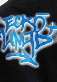 Juoda medvilninė marškinėlių su dideliu mėlynu grafiti stiliaus piešiniu su baltais akcentais, sklandžiai pereinančiu į išblukusią pilką foną.