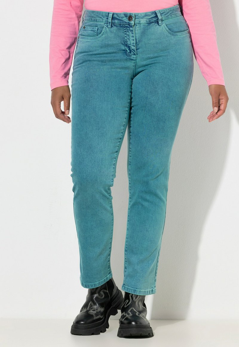 Turkusowe dżinsy z denimu o wąskim kroju, z pięcioma kieszeniami i talią o średnim stanie. Noszone z czarnymi, masywnymi butami. Tkanina o fakturze i gładkim wykończeniu.