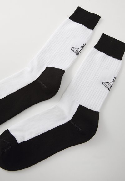 Baltas un melns sporta zeķes ar ribotu tekstūru, pastiprināta melna papēža un pirksta daļa, ar melnu logotipu sānos.