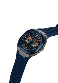 Kvadrāta zila silikona pulkstenis ar sudraba akcentiem, strukturēta ciparnīca, apelsīnu marķieri un hronogrāfa funkcijas. Metāla korpuss un sprādze.