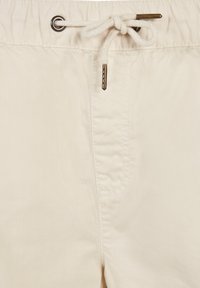 Lyse beige shorts med elastisk talje og snørre, der har en ensartet tekstur og metalbeslag ved snøren og lommerne.