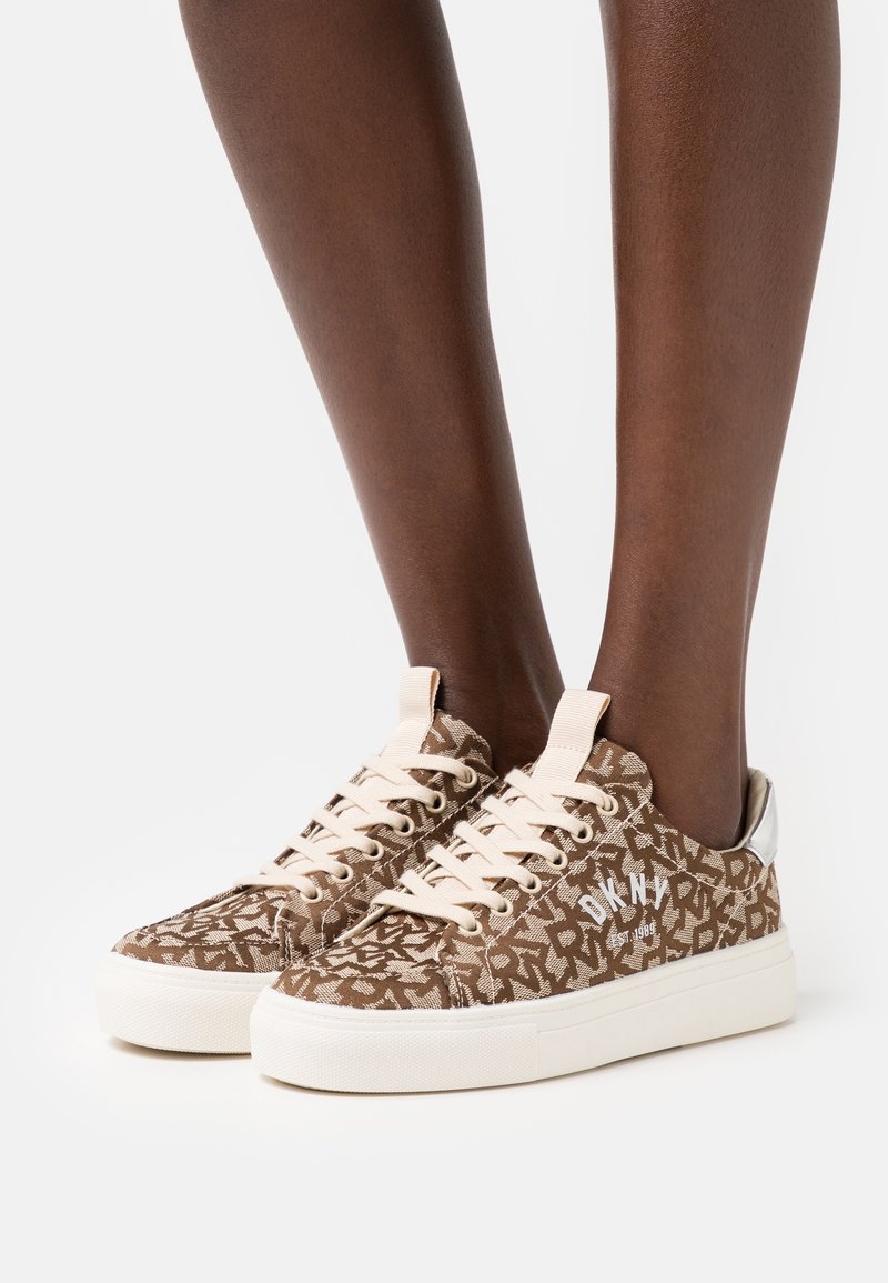 Bruna mönstrade kanvas sneakers med beiga snören och vita logodetaljer. Gummisula och silverdetaljer på hälen.