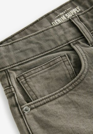 Khaki denim jeans featuring a front pocket, visible stitching, and a branded waistband. The fabric has a smooth, textured finish.