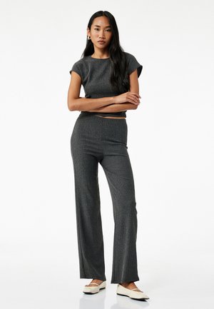 Grå strikket to-delt sæt bestående af en kortærmet crop top og høj talje, vide bukser. Glat tekstur med subtile lodrette linjer.