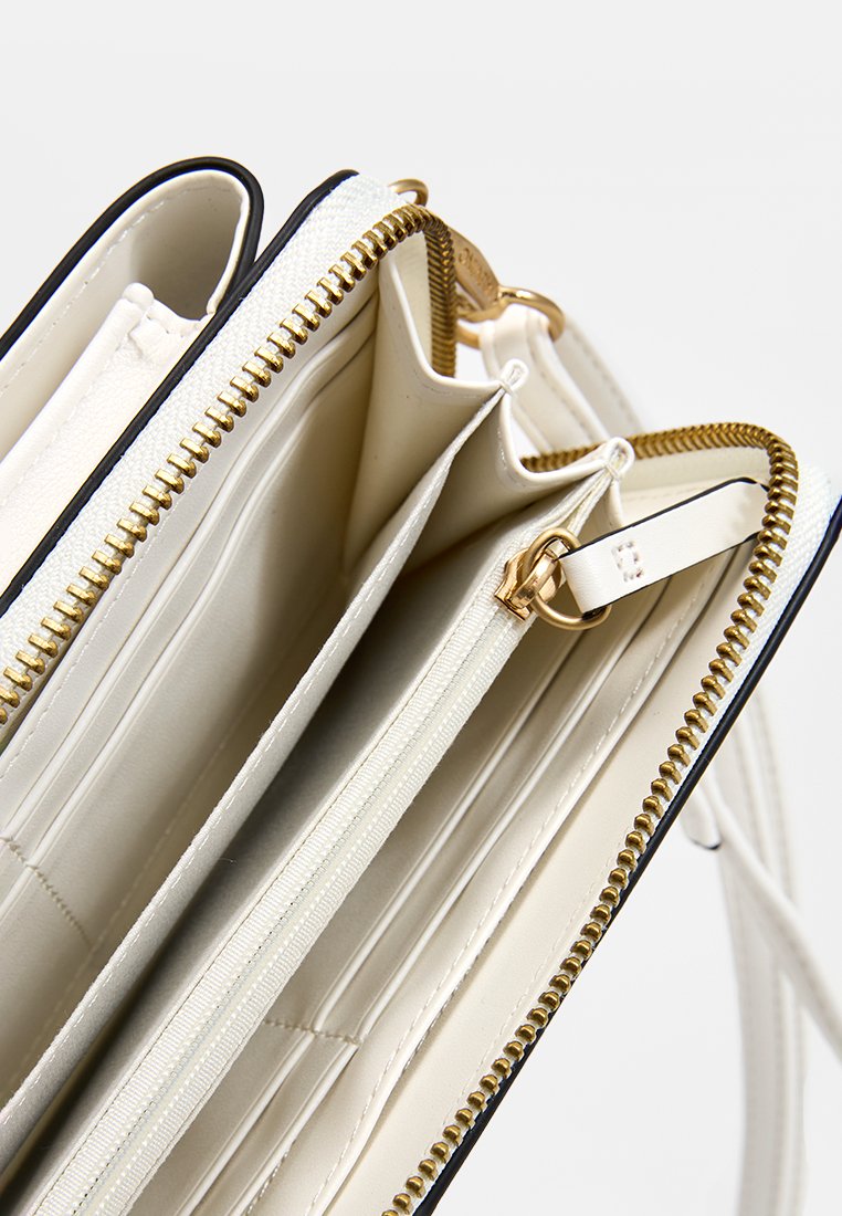 Portefeuille en cuir texturé blanc avec des zips dorés, plusieurs emplacements pour cartes et un intérieur lisse. Présente des bords contrastants en bleu marine et un porte-clés.