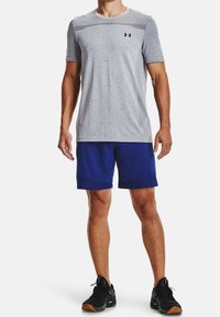 T-shirt de sport gris à manches courtes avec un motif texturé, associé à un short bleu uni et des baskets noires avec une accent en maille.