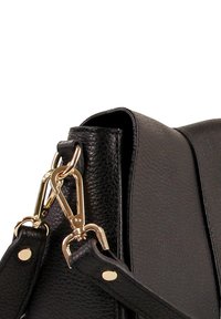 Zwarte leren handtas met een gestructureerde afwerking, voorzien van gouden hardware en stevige banden met decoratieve klinknagels en details van een kreeftsluiting.