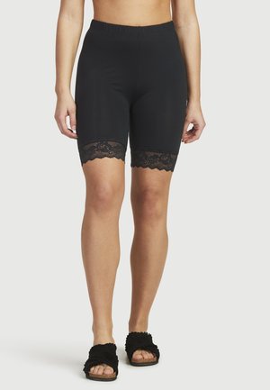 Svarta shorts med resårmidja och svart spetsdetalj vid fållarna. Tyget är slätt och elastiskt, vilket ger en figurnära silhuett.