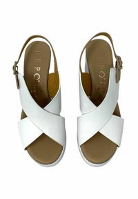 I sandali bianchi in pelle presentano un design con cinturini incrociati, una fibbia regolabile alla caviglia e una soletta marrone sagomata, con una finitura liscia e lucida.
