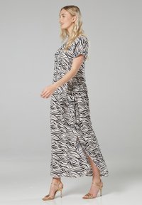 Maxikleid aus leichtem Stoff mit einem schwarz-weißen Zebra-Muster, kurzen Ärmeln und seitlichen Schlitzen für zusätzliche Bewegungsfreiheit.