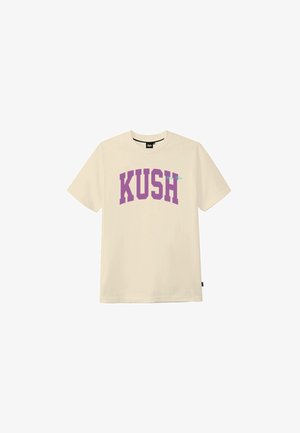 Camiseta beige de manga corta con texto en mayúsculas morado "KUSH" centrado en el frente, cuello redondo y pequeña etiqueta negra en la costura lateral.