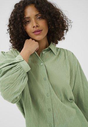 Hellgrünes Hemd mit Knopfleiste und strukturiertem Wellenmuster, mit langen Ärmeln und Kragen. Weicher Stoff mit legerer Passform.