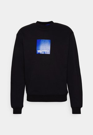 Sweatshirt noir avec un col rond, des poignets et un ourlet côtelés. Présente un logo rectangulaire bleu avec "KARL LAGERFELD JEANS" en texte blanc.