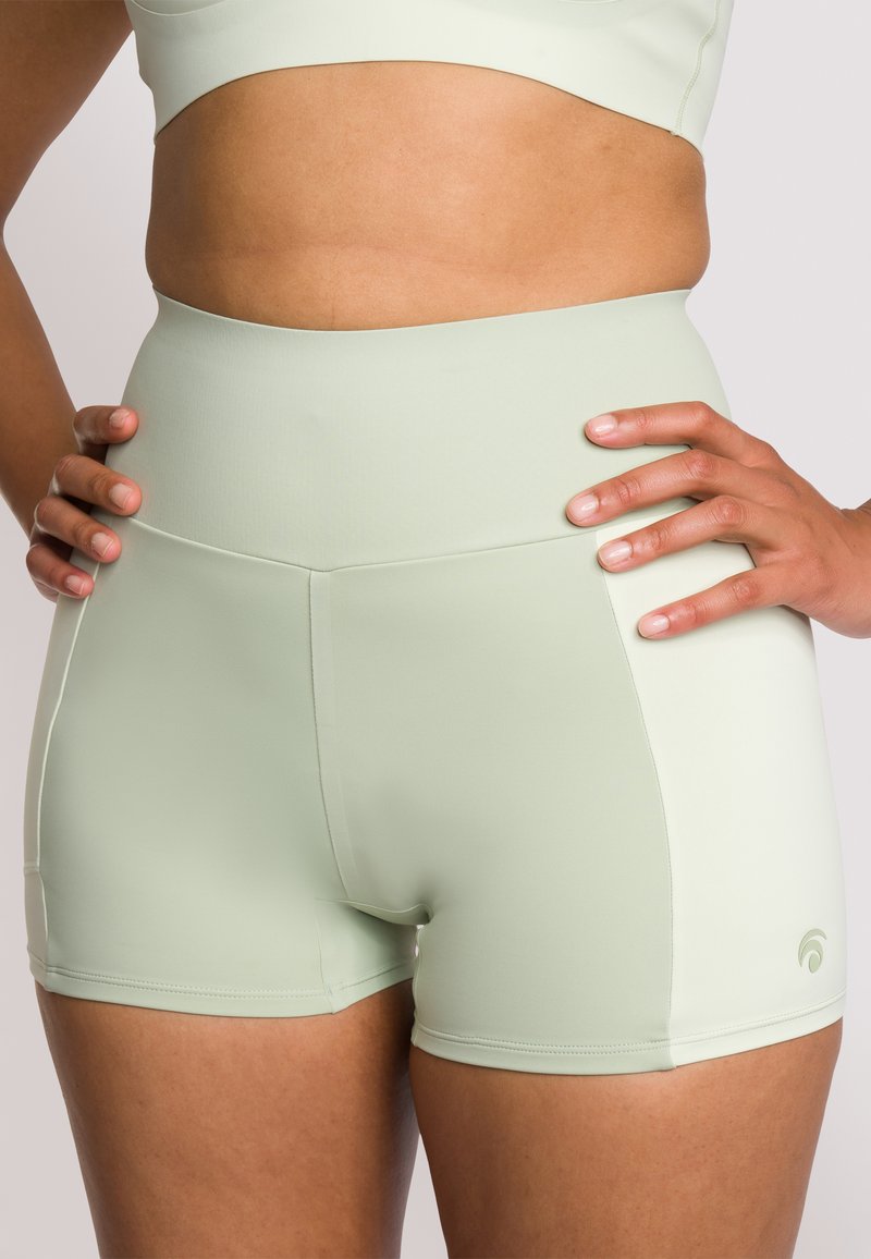 Pantaloncini a vita alta di colore verde chiaro, realizzati in tessuto elasticizzato, con una superficie liscia e sottili dettagli laterali.