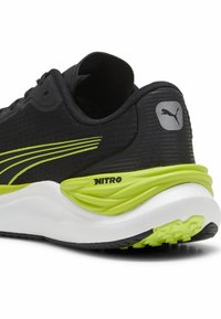 Zapatilla de running negra con acentos en verde lima, con parte superior texturizada, suela acolchada y la marca "NITRO" en el talón.