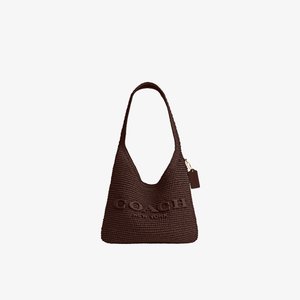 Borsa a tracolla Coach marrone intrecciata con tracolla larga e logo "Coach New York" in rilievo sul davanti, con una piccola targhetta appesa.