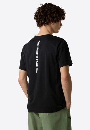 Black cotton t-shirt with a crew neck, featuring vertical white branding on the back. Short sleeves and a relaxed fit.