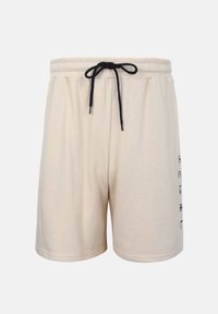 Μπεζ casual σορτς με ελαστική μέση και μαύρο κορδόνι, με μικρό μαύρο κείμενο στη δεξιά πλευρά.