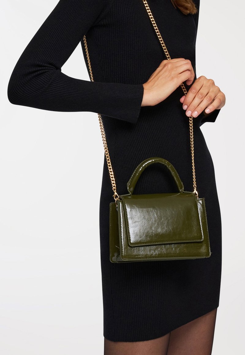 Borsa a tracolla in pelle verniciata verde con manico superiore e tracolla in catena dorata regolabile. Presenta una pattina frontale e una superficie testurizzata.