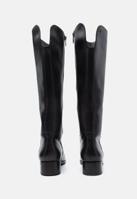Schwarze Lederstiefel bis zum Knie mit einem leicht ausgestellten Schaft, seitlichen Reißverschlüssen und einem Blockabsatz. Glatte Textur mit minimalen Nahtdetails.