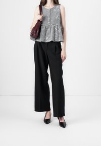 Zwart-witte geruite peplumtop met een ronde halslijn en knopen, gecombineerd met hooggesneden zwarte wijde broekspijpen en zwarte puntige hakken.