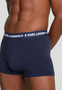 Sötétkék pamut boxeralsó fehér elasztikus derékkal, amelyen a "KARL LAGERFELD" felirat található. Zökkenőmentes textúra, testhezálló dizájn.