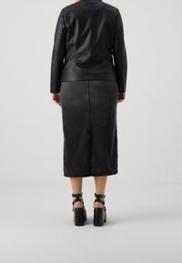 Black leather jacket and dark denim skirt, both mid-length. Paired with chunky black heeled sandals featuring ankle straps.