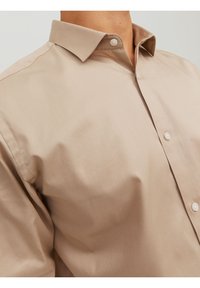 Beige overhemd met knopen, gemaakt van glad katoenen stof, met een puntige kraag en zichtbare knopen, met een getailleerde pasvorm en minimalistisch ontwerp.