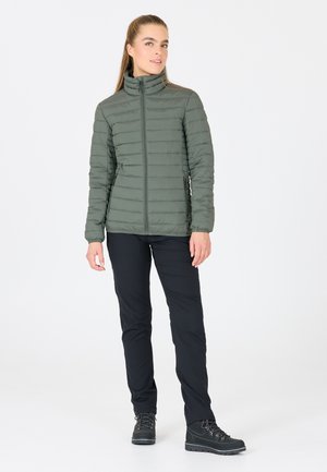 Olivgrön pufferjacka med vertikal sömnad, hög krage och frontal dragkedja. Matchat med svarta friluftsbyxor och grå vandringskängor.