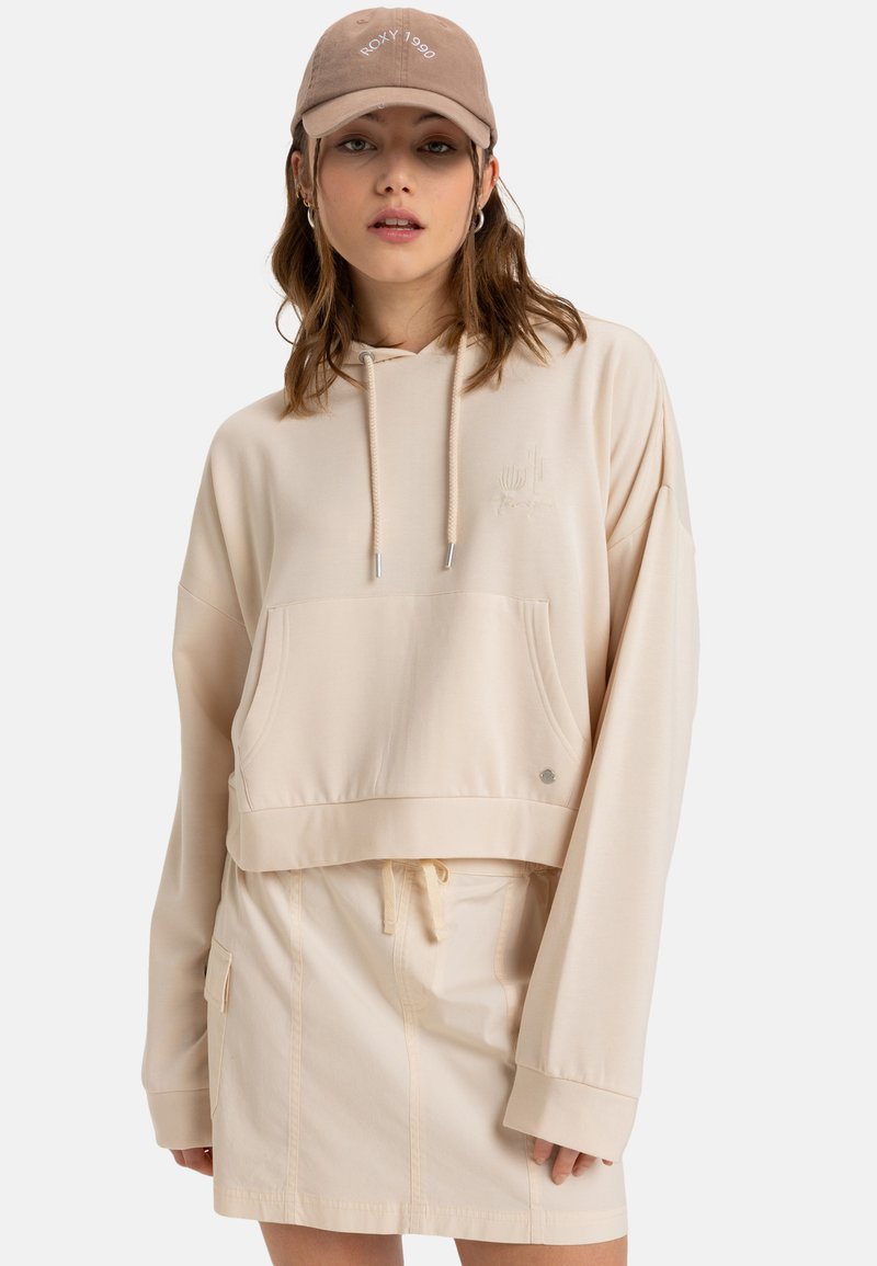Cream cropped hoodie with a front pocket, drawstring, and embroidered detail. Paired with a matching beige miniskirt with a side pocket.