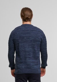 Granatowy sweter z dzianiny z teksturowanymi rękawami w warkocz oraz prążkowanym okrągłym dekoltem. Miękka, mieszana tkanina o lekko melanżowym wyglądzie.