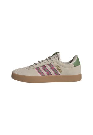 Beige Adidas lage sneaker met gumzool, roze en groene camo-strepen, groene hieltab en mesh tong.