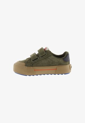 Sneaker verde oliva a taglio basso con due strap in Velcro, suola in gomma beige con striscia arancione e suola esterna blu texturizzata.