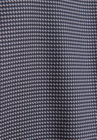 Tessuto blu navy con un motivo geometrico testurizzato in tonalità più chiare, che crea un effetto tridimensionale. Superficie liscia con un design moderno.