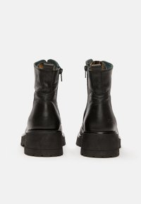 Botas de cuero negro hasta el tobillo con un acabado texturizado, cremalleras laterales y una suela de goma gruesa. El forro interior presenta un patrón colorido.